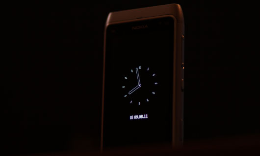 Das Nokia N8 steht bei Nacht als Wecker auf einem Tisch